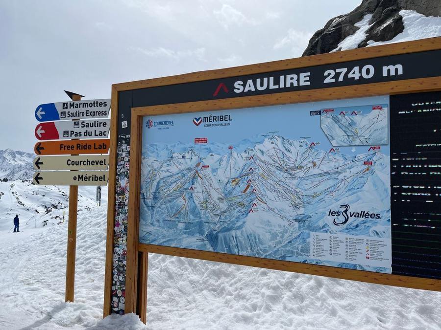 A large piste map and direction signs on the mountain.