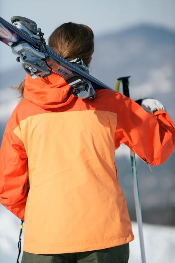A person carrying skis over a shoulder.