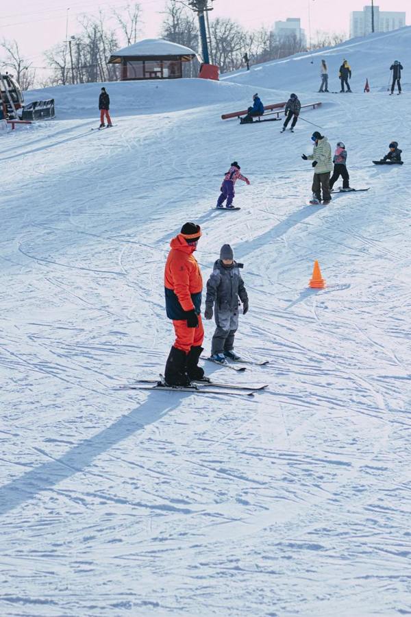 Skiers on a gentle practice slope beside a safety net.