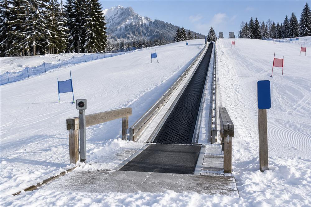 A beginner conveyor lift on a gentle snowy practice slope