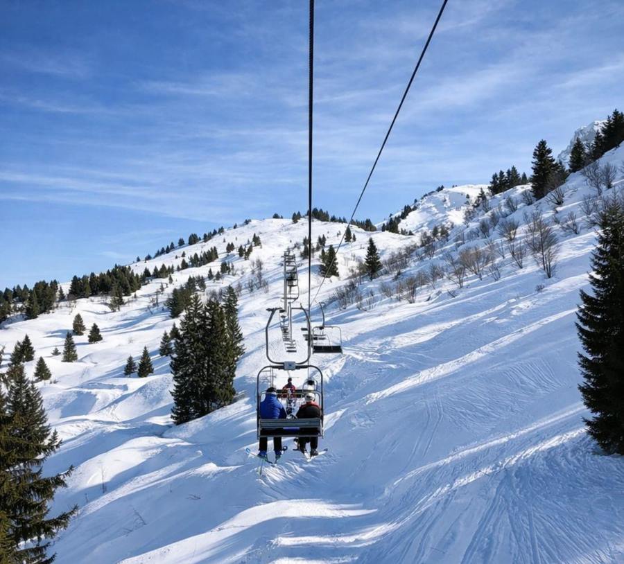 Occupied chairlift seats above a snowy slope.