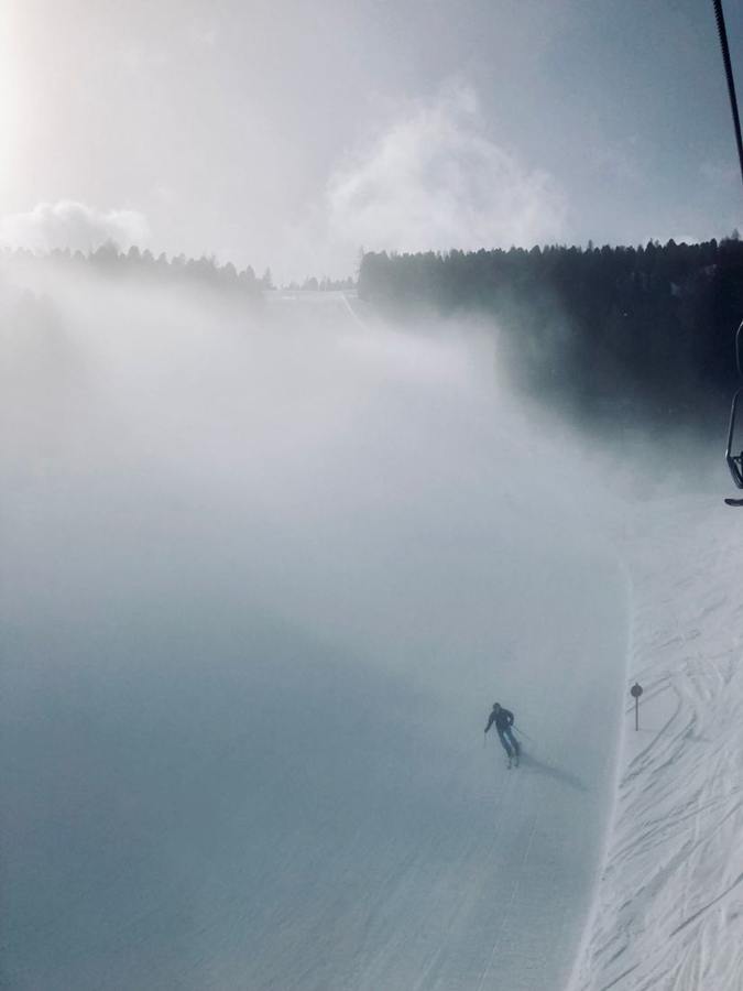 A skier in fog on a snowy slope.