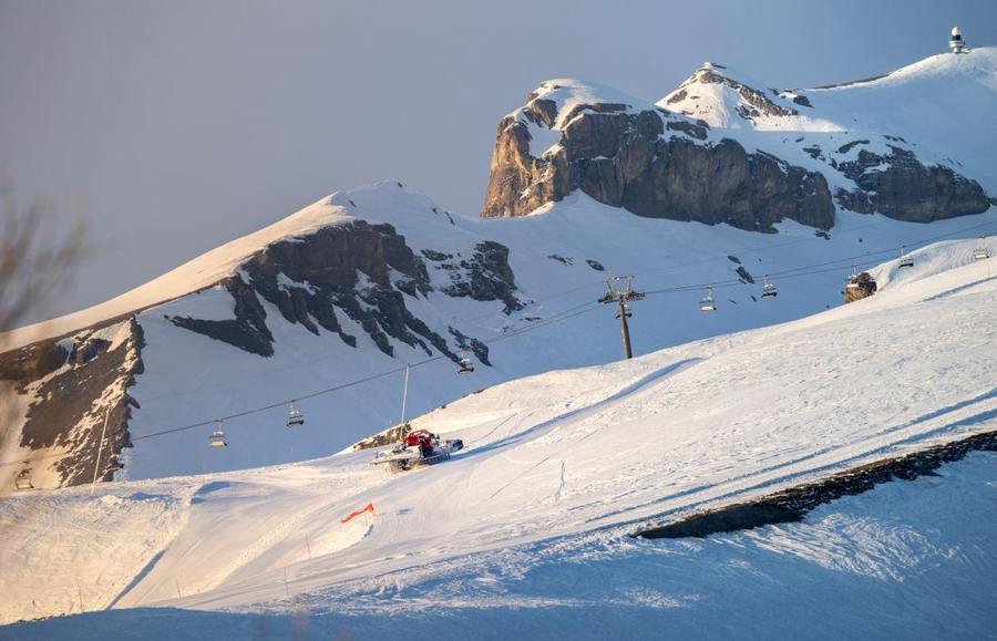 A groomed slope and ski lifts in evening light.