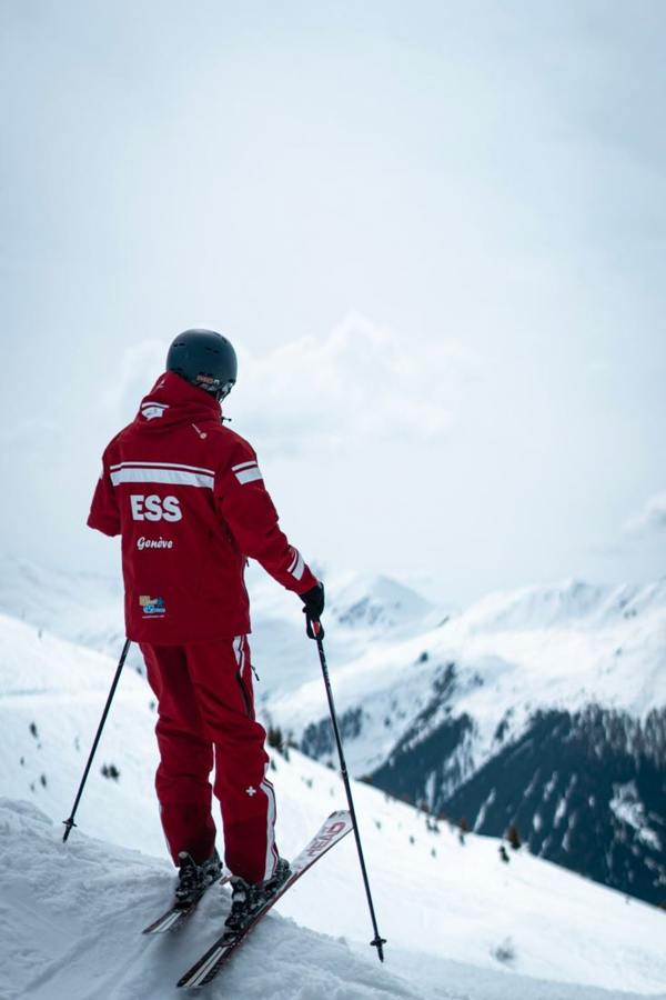 A skier in red clothing standing with poles on a slope.