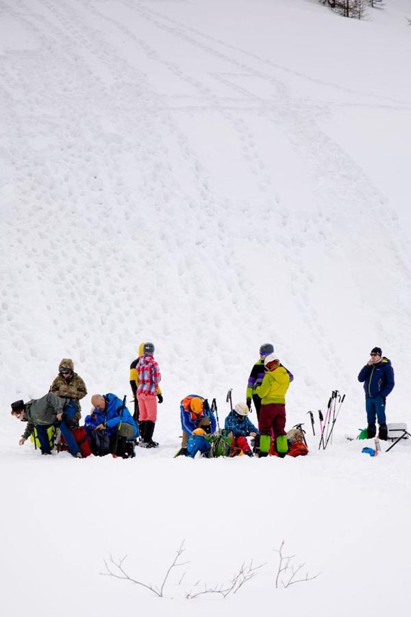 A small group with winter equipment beside an open snowfield.