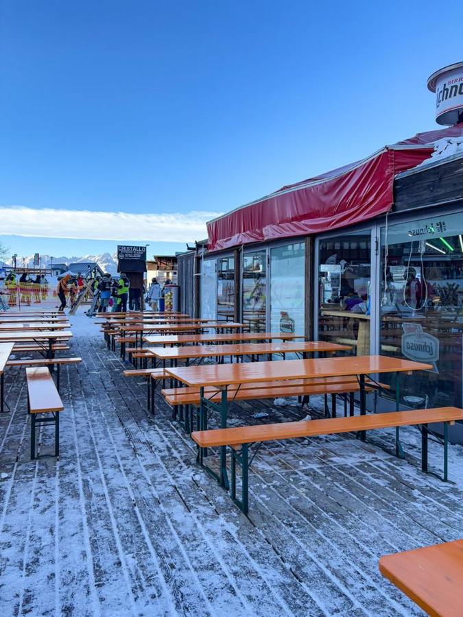 Wooden tables on a snowy ski resort terrace.