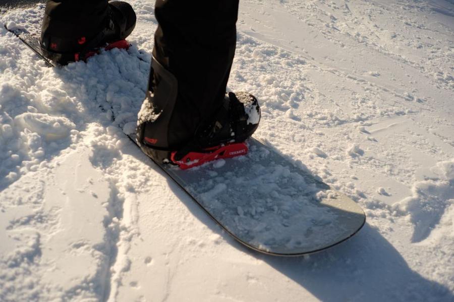Snowboard boots in bindings on a snowboard in the snow.