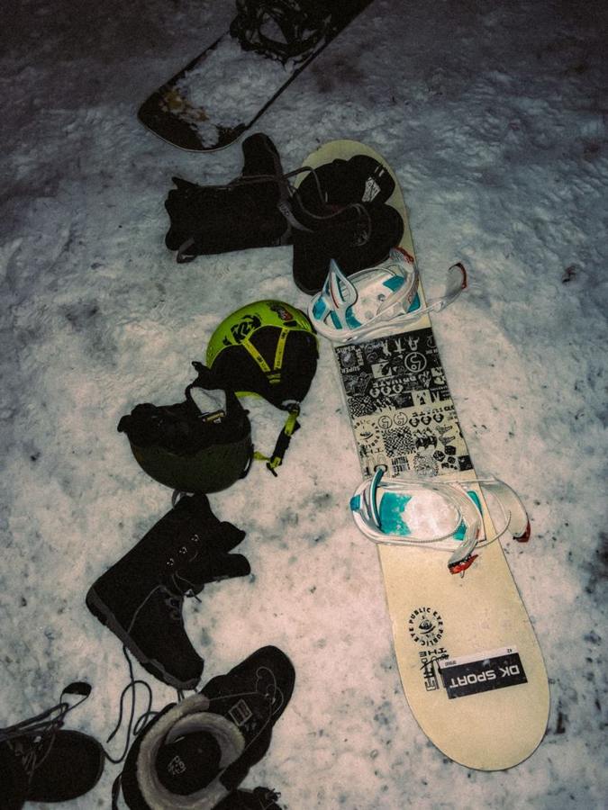 A snowboard, helmet and other equipment lying on snow.