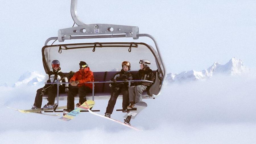 Skiers and snowboarders share a chairlift.