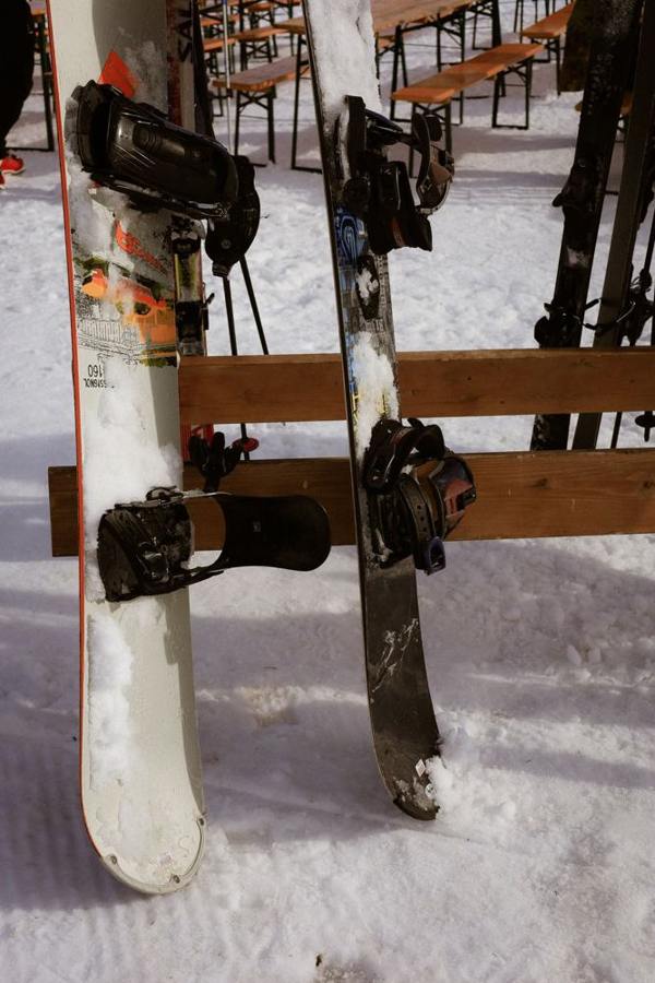 Two snowboards with bindings lean against a wooden rack in the snow.