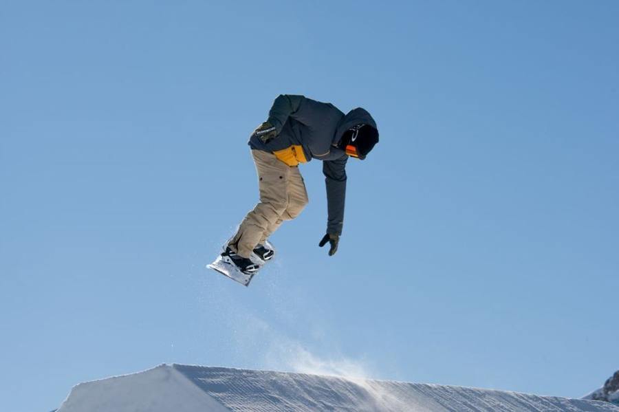 A snowboarder jumps above a feature in a snowpark.