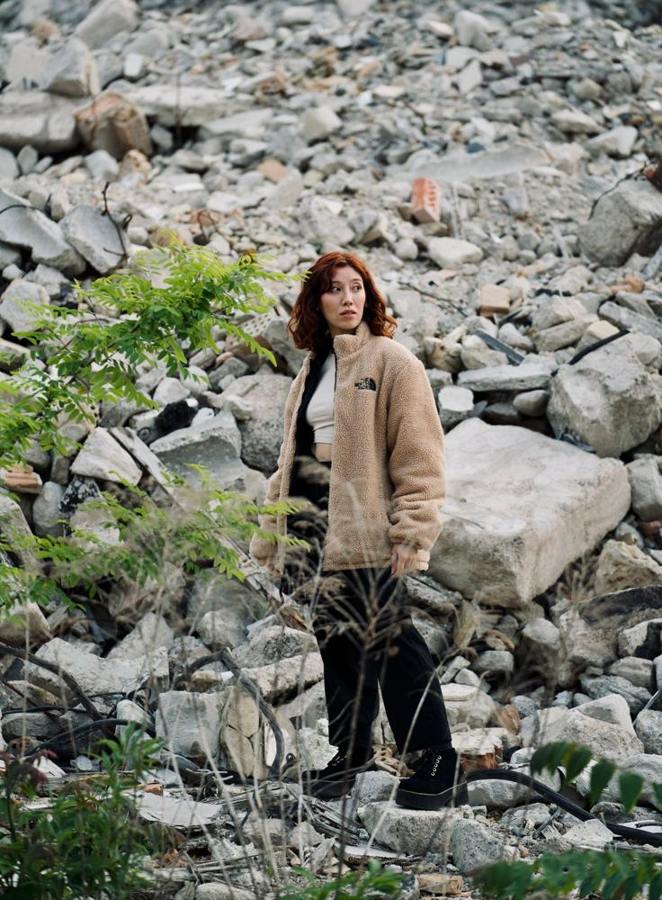 A woman wears a fleece jacket in rocky terrain.