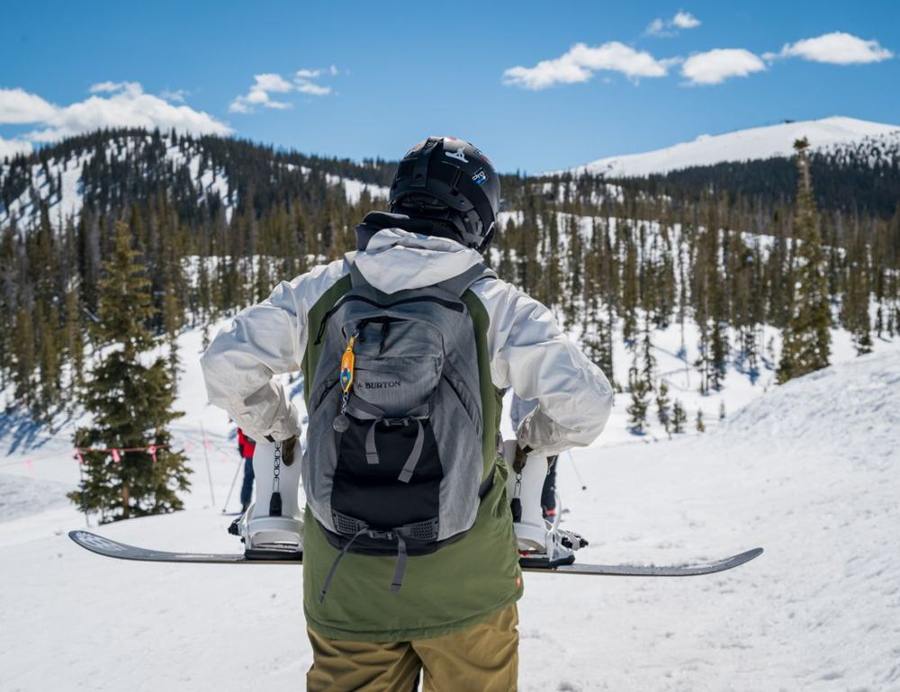A snowboarder wears a backpack on a snowy slope.