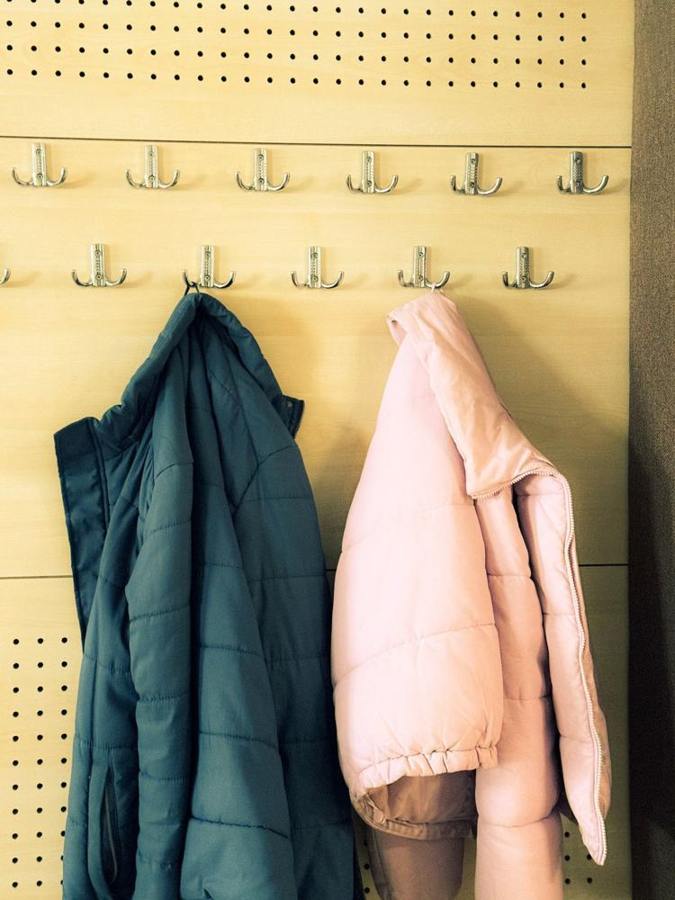 Two padded winter jackets hang on hooks.
