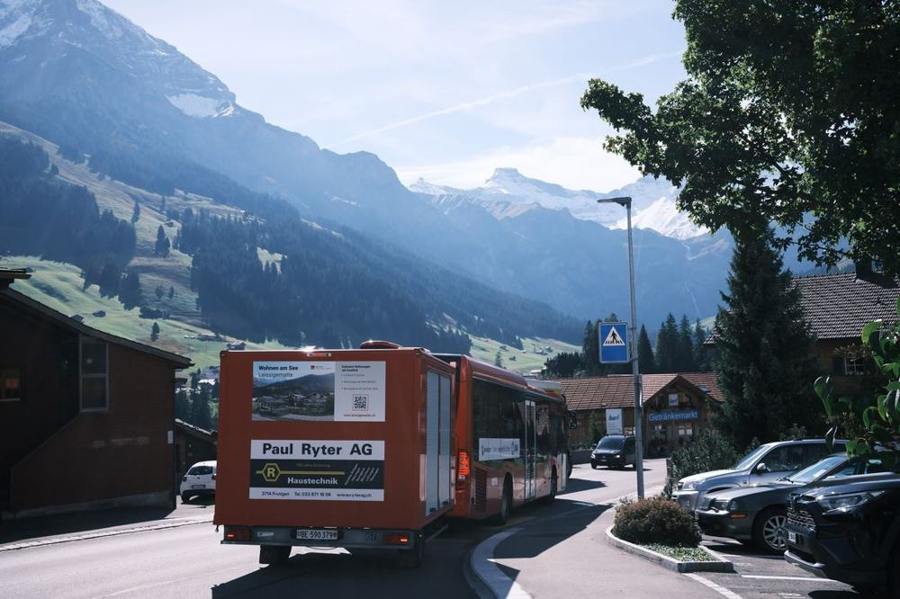 A red bus travels through a Swiss mountain village.