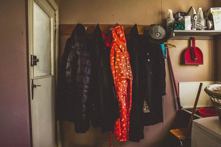 Winter jackets hang on hooks in a utility room.