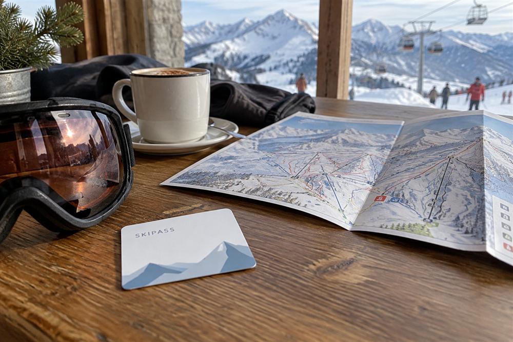 An illustrative ski lift pass card beside a folded piste map