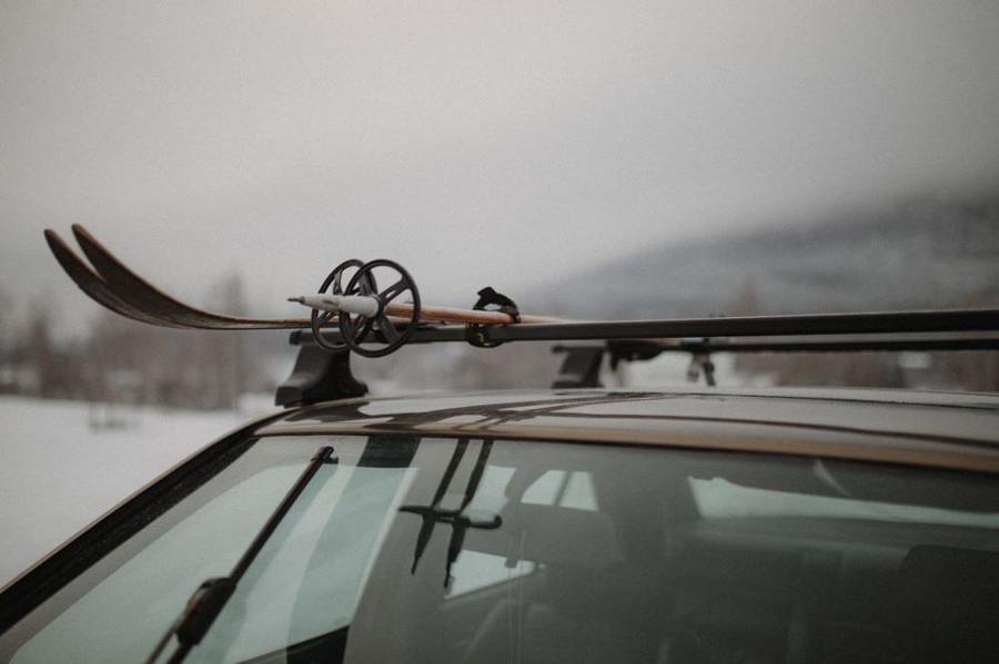 Skis and poles rest on a car roof rack.
