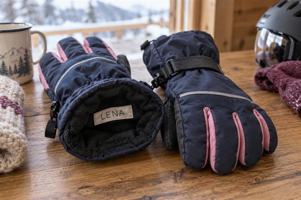 A child’s insulated snow glove with a sewn-in name label at the cuff
