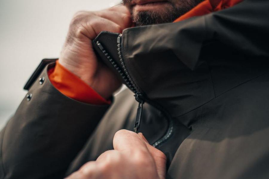 Close-up of hands fastening the zipper of a winter jacket.