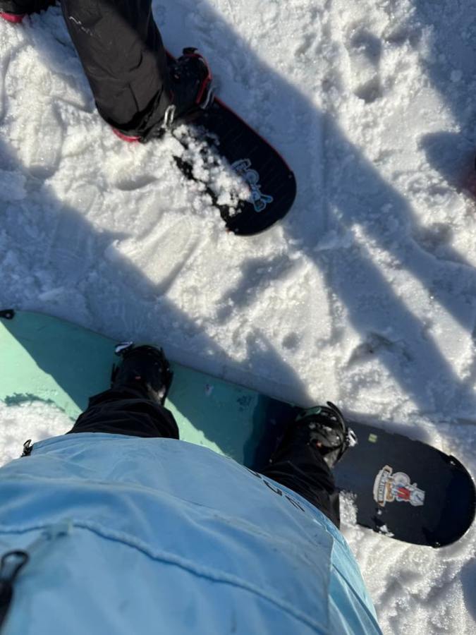 Two snowboards with boots and bindings rest on a snowy slope.