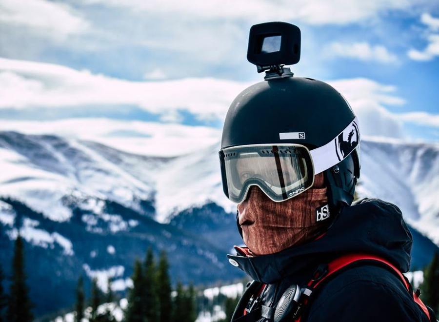 A person wears a ski helmet with a camera and goggles.