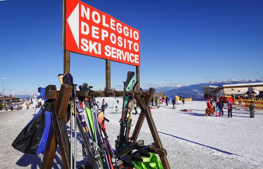 Skis and poles stand beside a signed ski rental station.