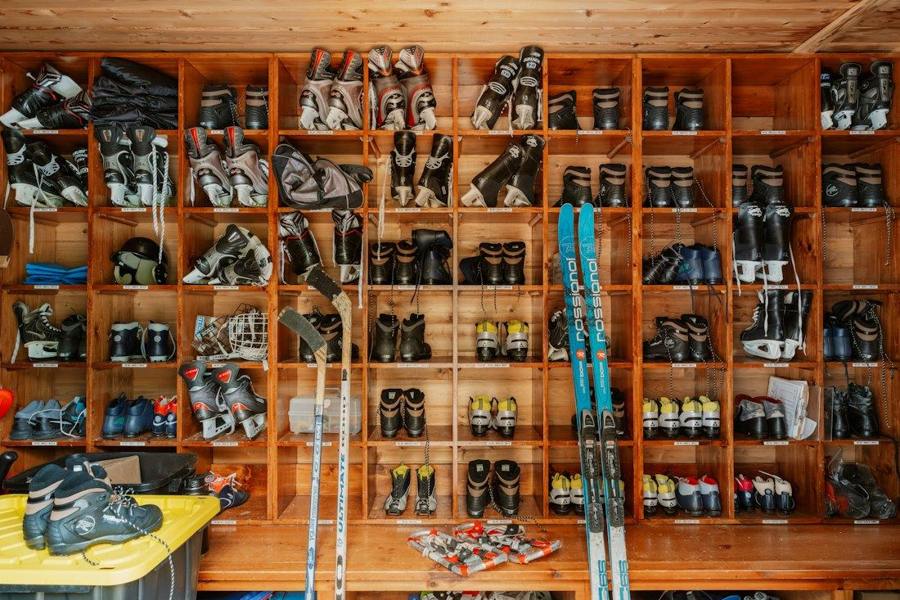 Winter sports equipment is organised in wooden compartments along a wall.